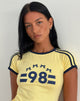 Image du tee-shirt Salda en limonade avec reliure marine et emblème '98'.